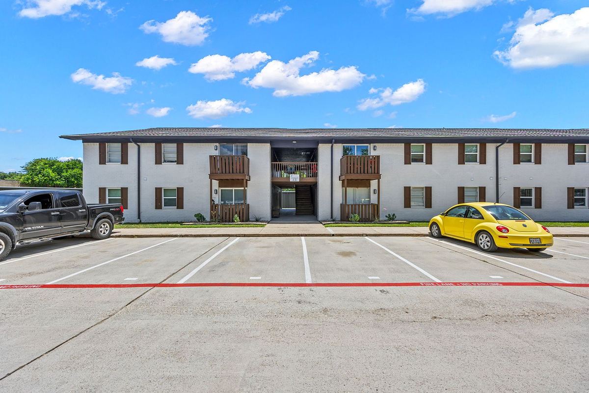 Two-story white brick building with wood balconies and fresh parking stripes