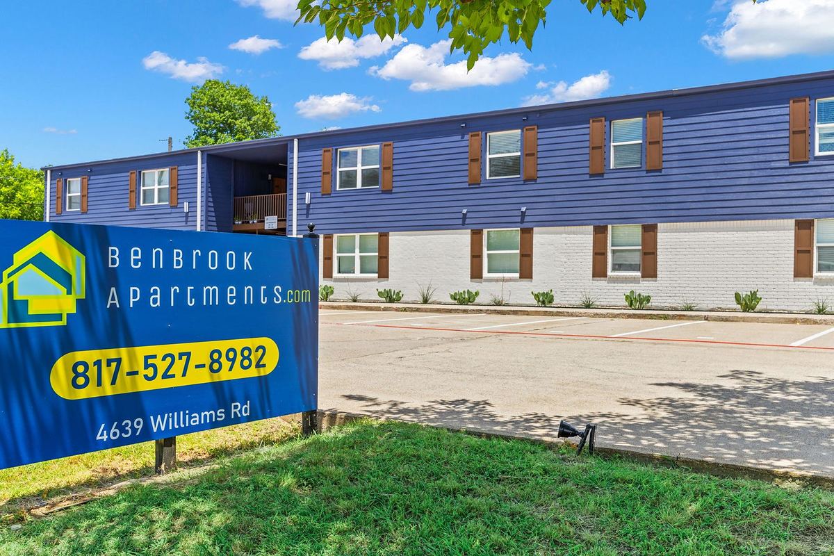 Benbrook Apartments sign with phone number in front of the navy and white building