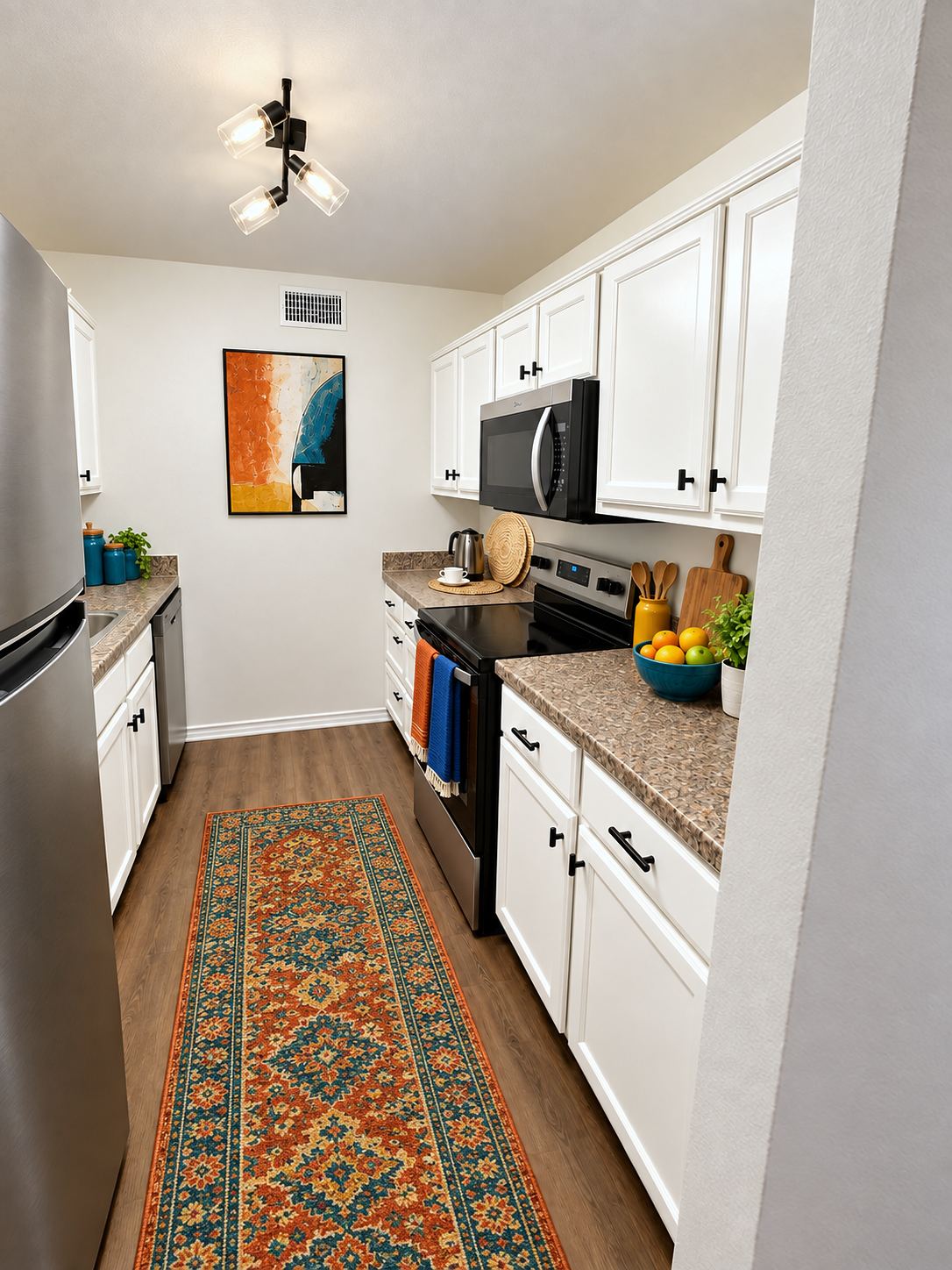 Galley kitchen with white cabinets, black hardware and stainless steel appliances