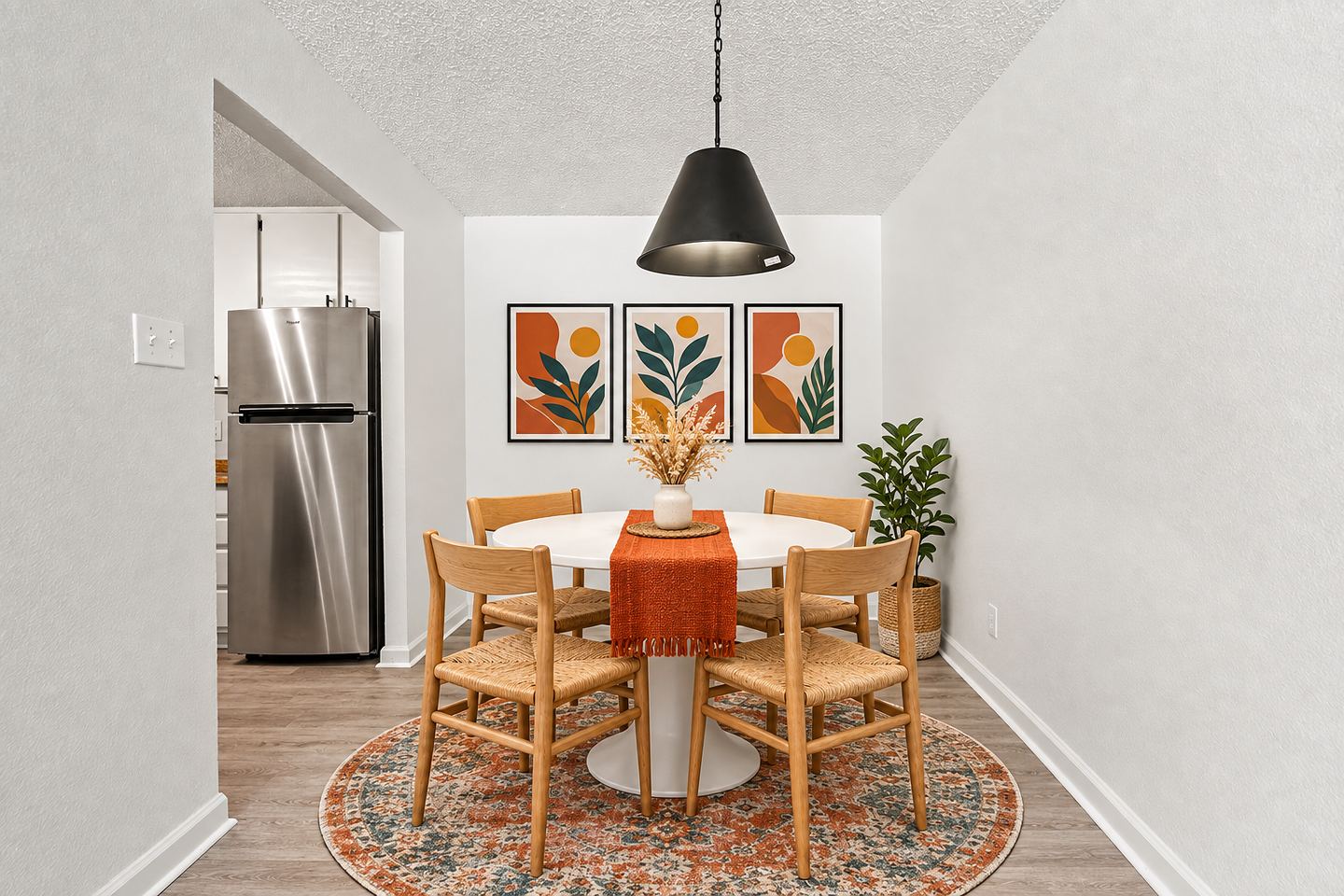 Dining nook with round table, pendant light and a view into the kitchen