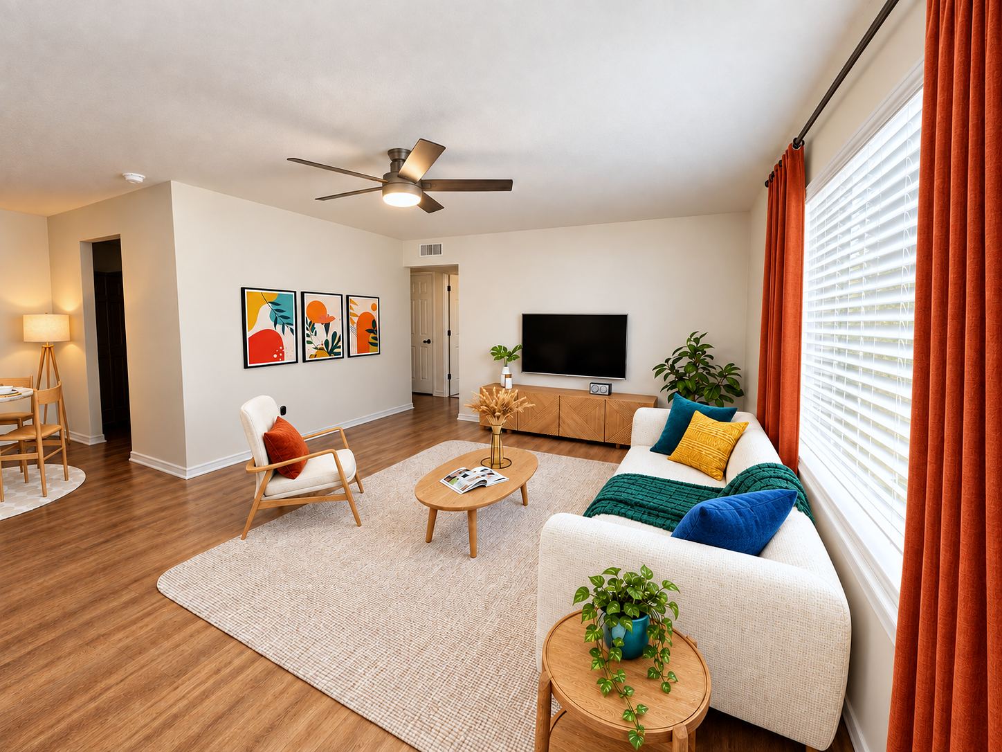 Staged living room with plank floors, ceiling fan, large window and modern furnishings